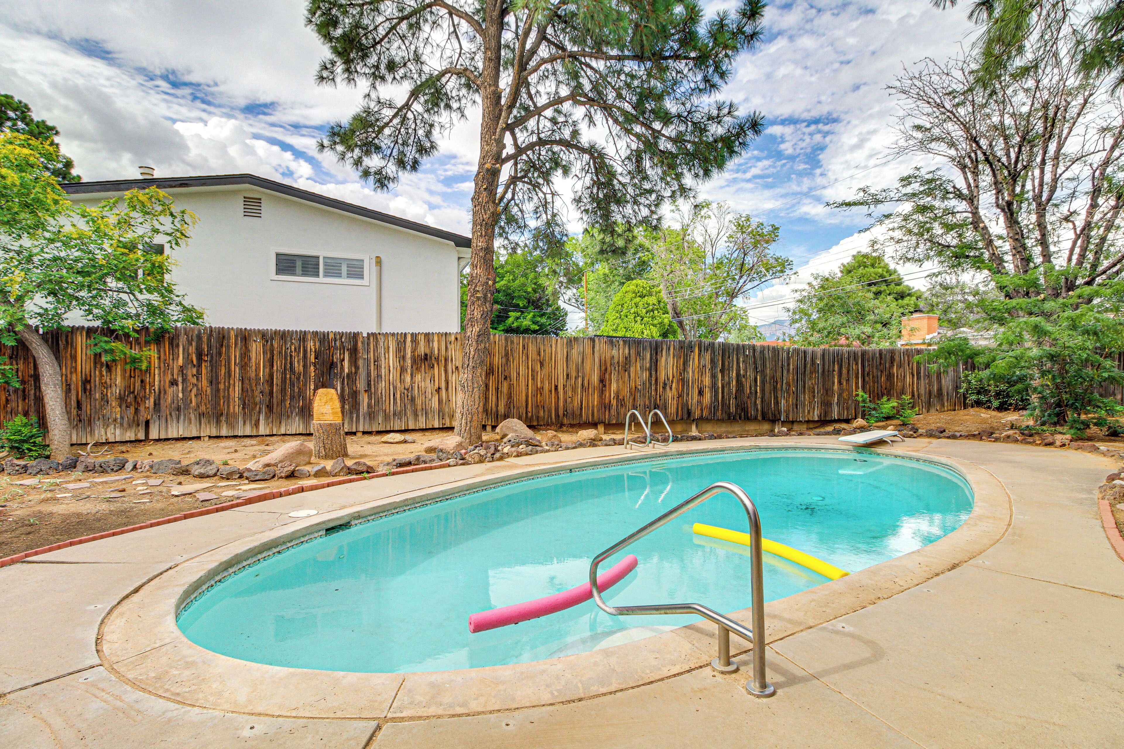 Un patio trasero con piscina, valla de madera y una casa.