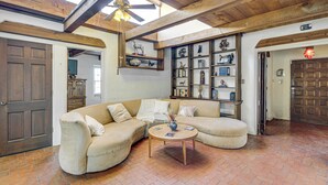 A spacious living room with a curved sectional sofa, a wooden ceiling, and a brick floor. - Gorgeous Adobe Home: Classic Santa Fe Style in ABQ (Albuquerque)