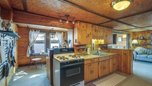 L’intérieur d’un chalet rustique comprend une cuisine centrale, des murs en bois, un coin repas et un espace de vie chaleureux.