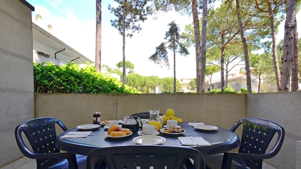 Une table ronde, des chaises, des assiettes remplies de nourriture, des tasses et une carafe.