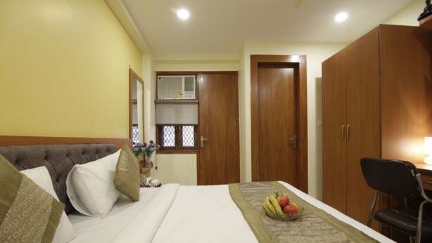 A hotel room with a bed, a desk, and a wardrobe. - Hotel TMS Grand (New Delhi)