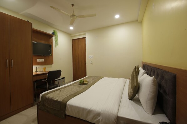 Un dormitorio con cama, escritorio, silla y televisor.