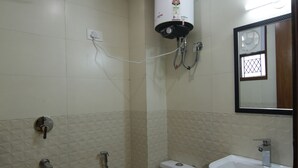 A small bathroom with a toilet, bidet, and sink. - Hotel TMS Grand (New Delhi)