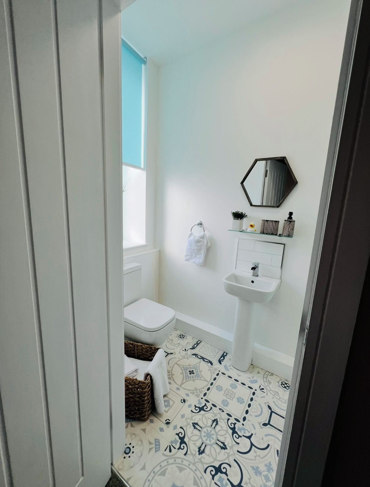 A bathroom with a toilet, sink, and decorative tiles.