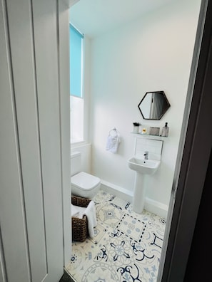 A bathroom with a toilet, bidet, sink, and a mirror on the wall.