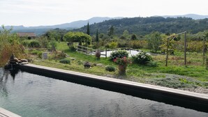 A serene landscape with a water feature, a stone structure, and a wooden bridge. - Holiday Home 'Eco Gîte' with Mountain View, Wi-Fi and Air Conditioning (Payzac)