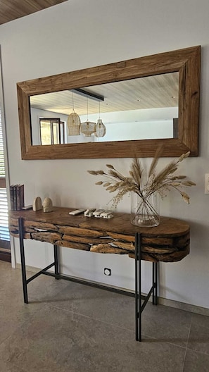 A wooden console table with a mirror above it, a vase with dried flowers, and a hanging light fixture. - VILLA MODERNE EN CORSE - Sea and mountain views, swimming pool, pool house (CALENZANA)