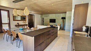 Una cucina moderna con un'isola grande, mobili in legno e un'area pranzo con sedie.