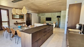 Una cocina moderna con una isla grande, armarios de madera y un comedor con sillas.