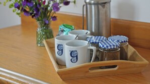 A tray with coffee mugs, a thermos, and spice jars on a wooden table. - Glenuig Inn (Lochailort)