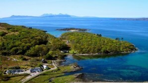 A coastal landscape with a small settlement, clear blue waters, and distant mountains. - Glenuig Inn (Lochailort)