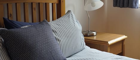 A bed with striped bedding, a wooden headboard, and a bedside lamp.