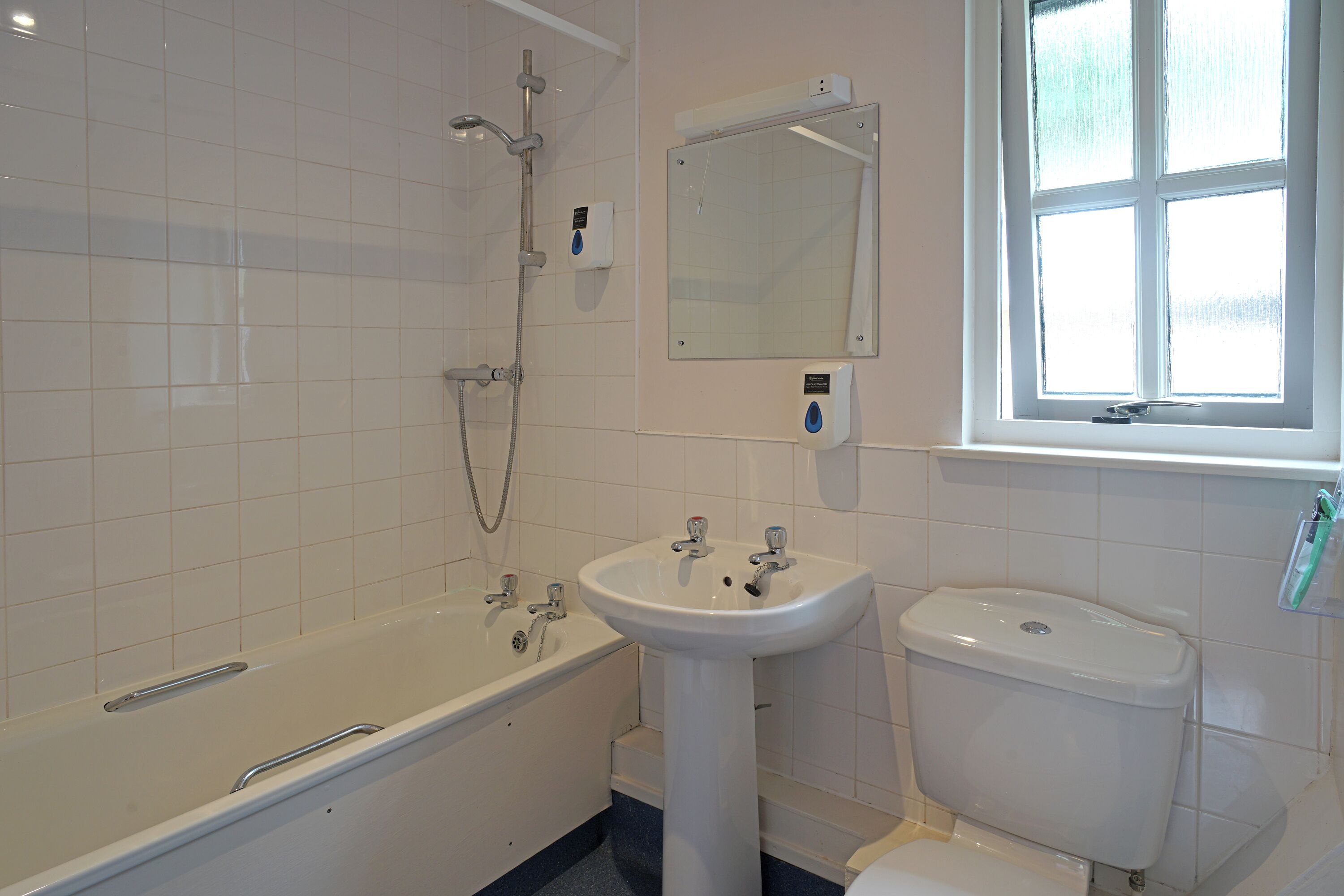 A bathroom with a bathtub, sink, toilet, and a window.