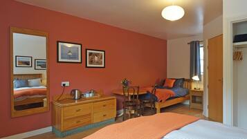 A bedroom with a bed, a dresser, a chair, a desk, and a mirror.