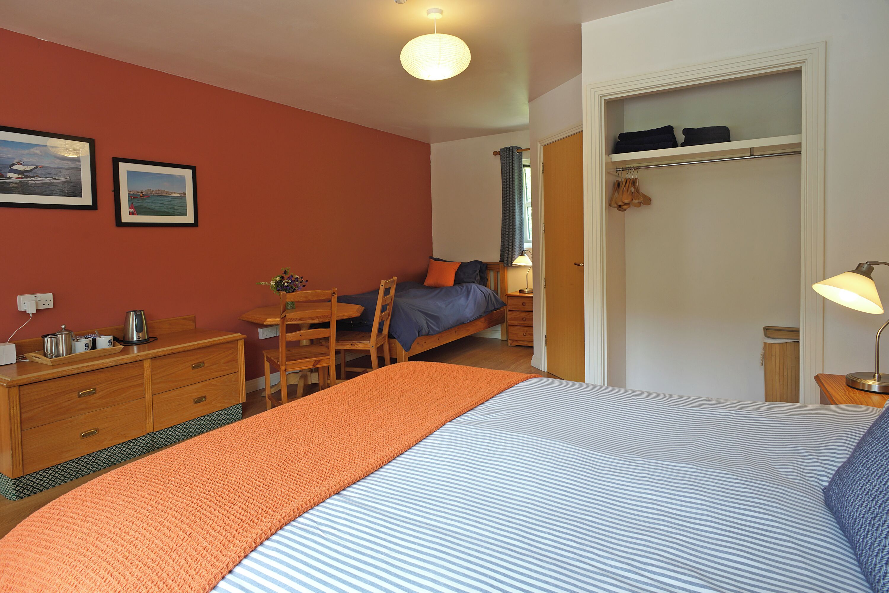 A bedroom with a bed, a desk, a chair, a wardrobe, and a window.