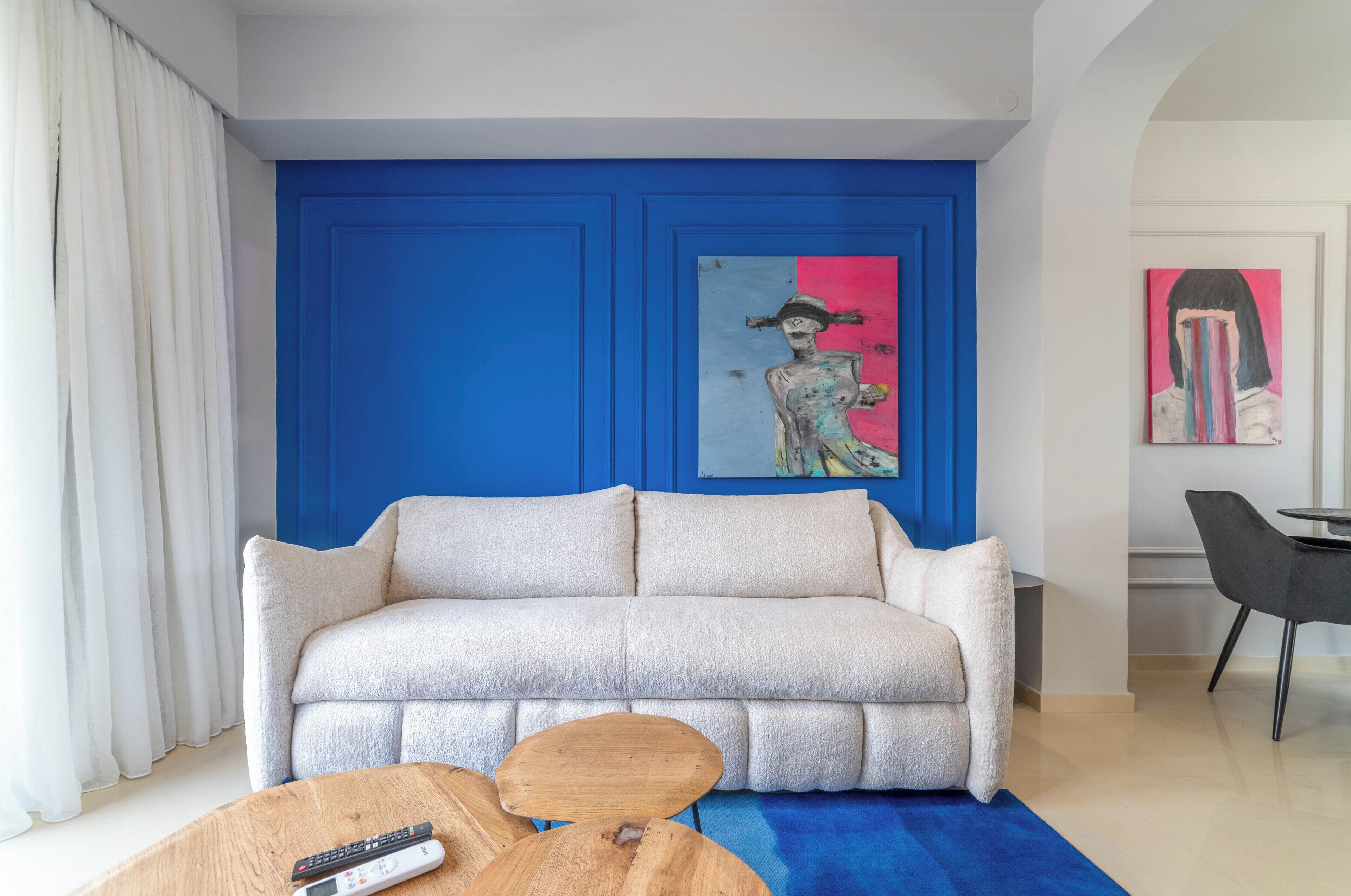 A living room with a white sofa, a blue accent wall, and artwork.