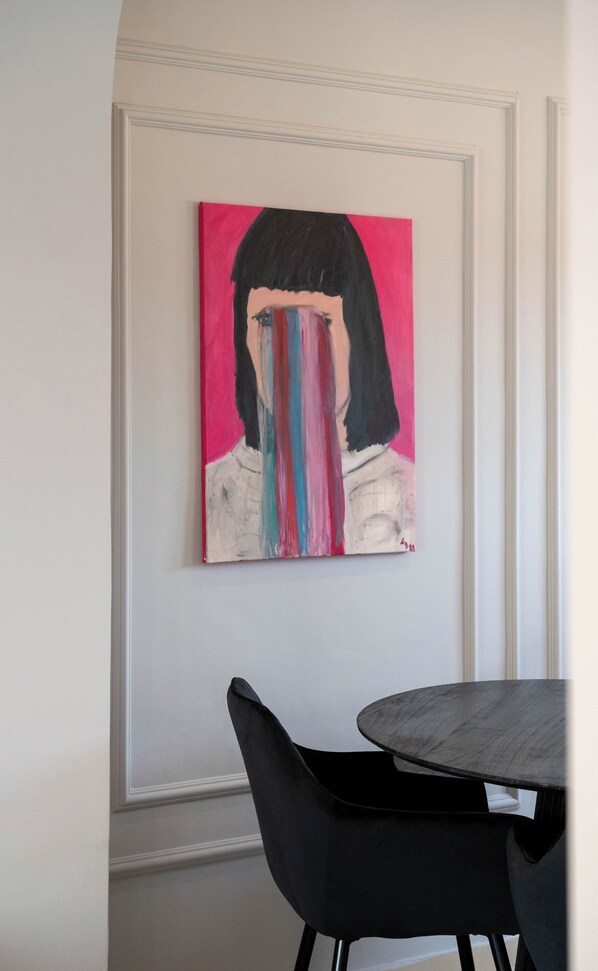 Una pintura de una mujer con un rostro de rayas coloridas sobre una pared blanca.