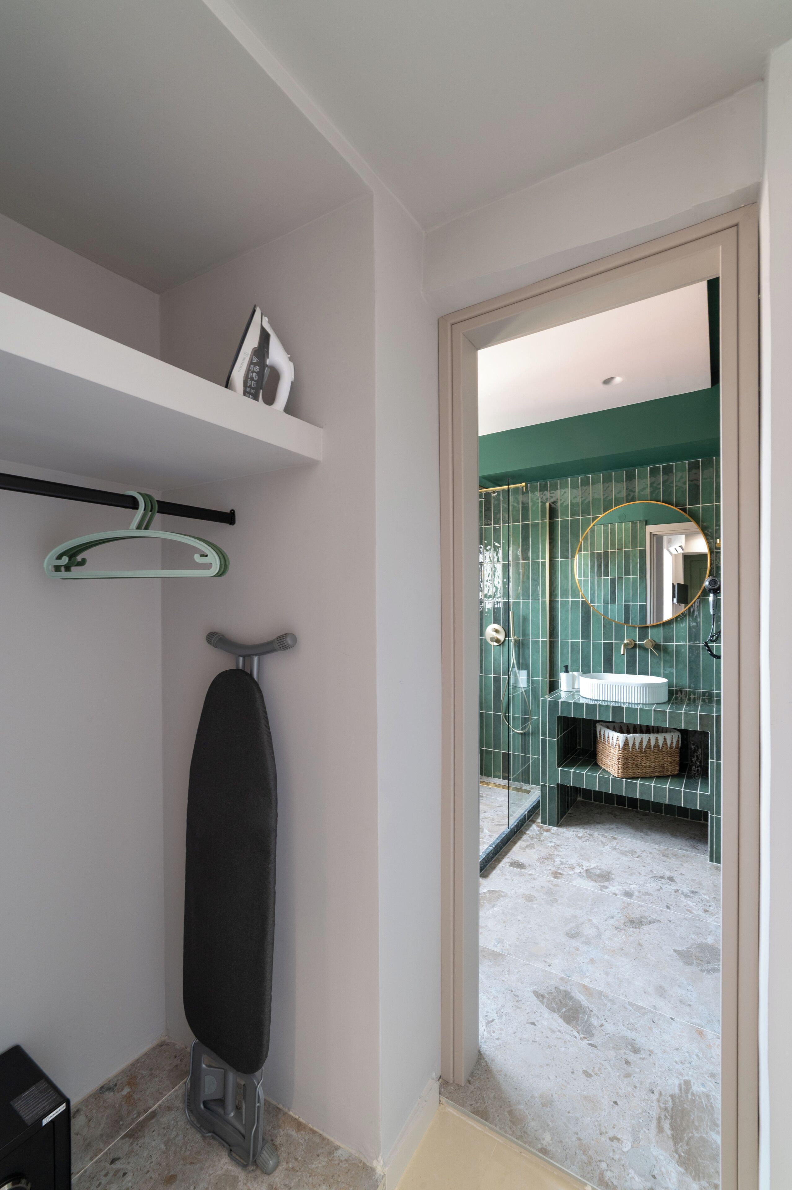 Une salle de bain avec un mur recouvert de carreaux verts, un lavabo blanc, un miroir et un porte-serviettes mural.