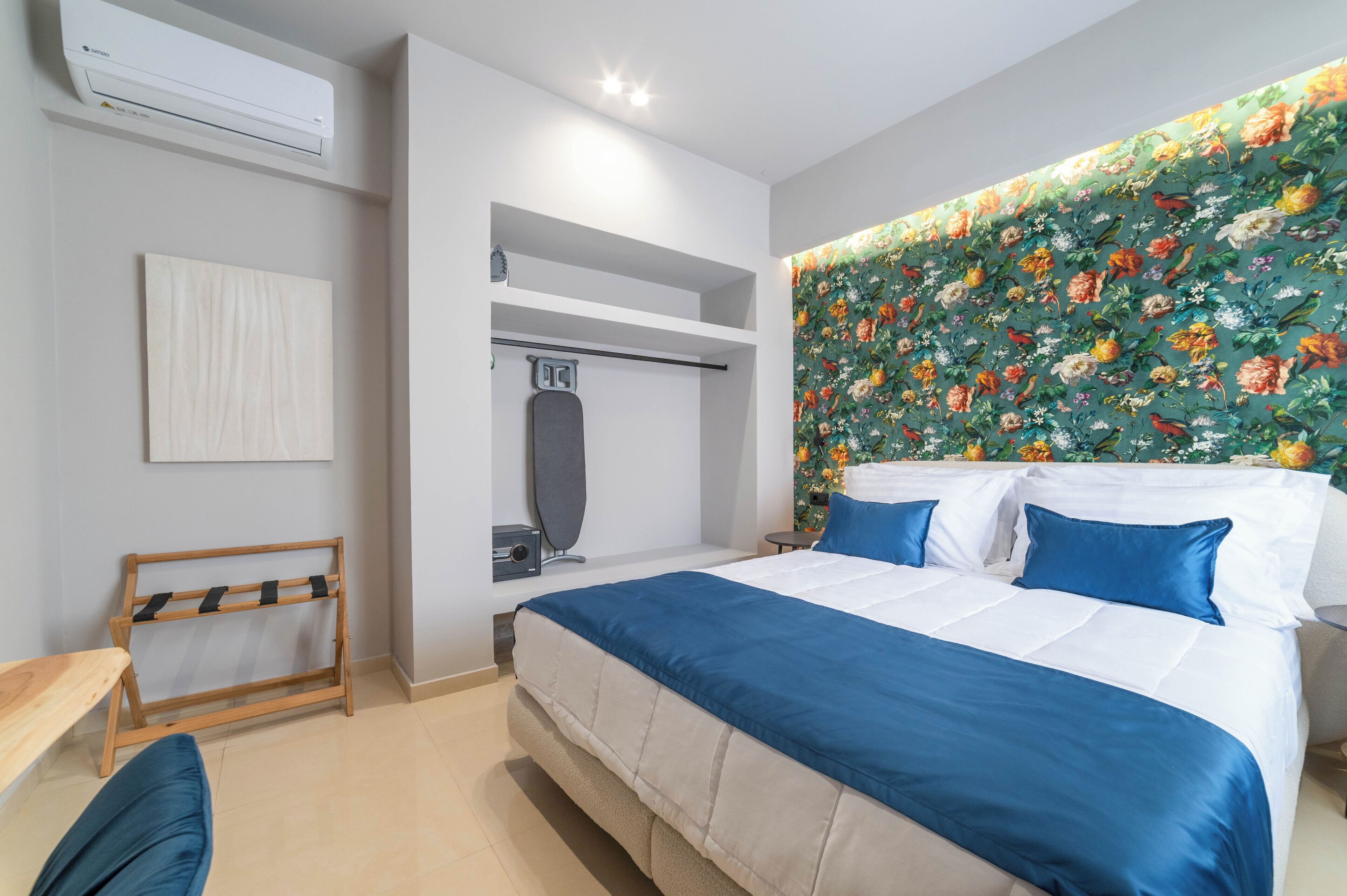 A bedroom with a large bed, a wardrobe, a mirror, and a wall-mounted air conditioner.