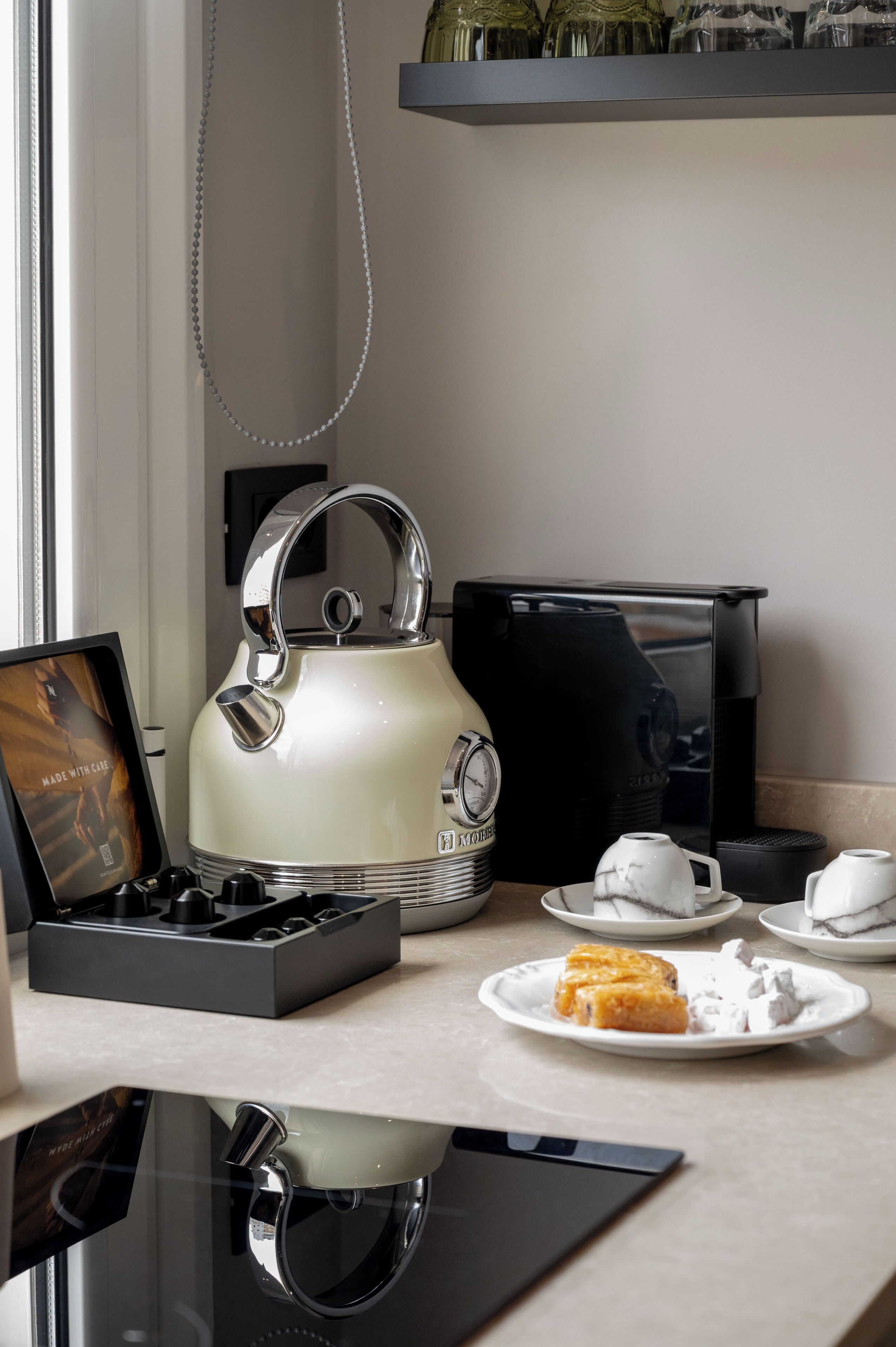 Une cuisine équipée d’une bouilloire, d’une machine à café et d’une assiette contenant de la nourriture.