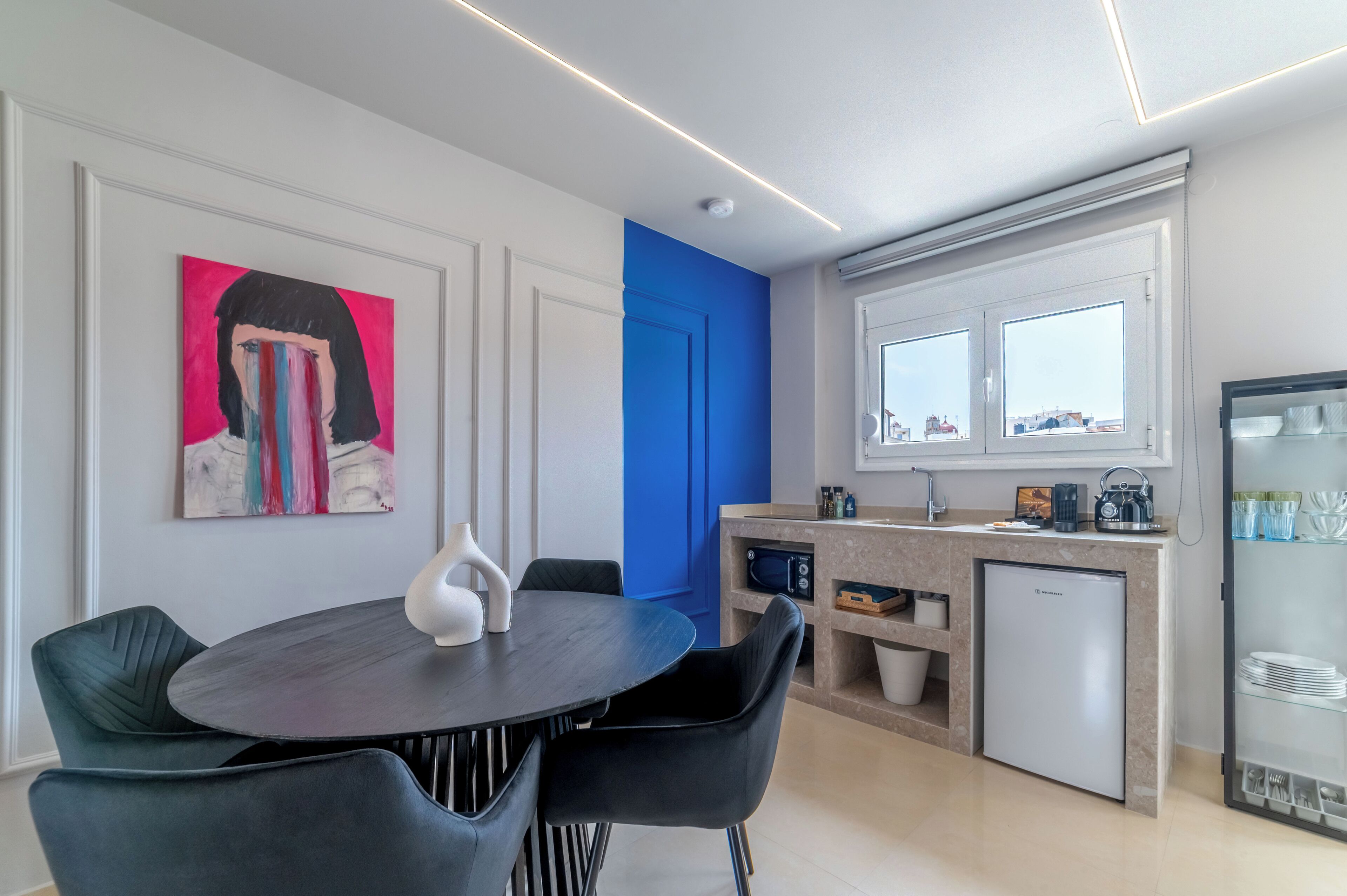 A modern kitchen with a built-in refrigerator, a coffee machine, and a window above the sink.