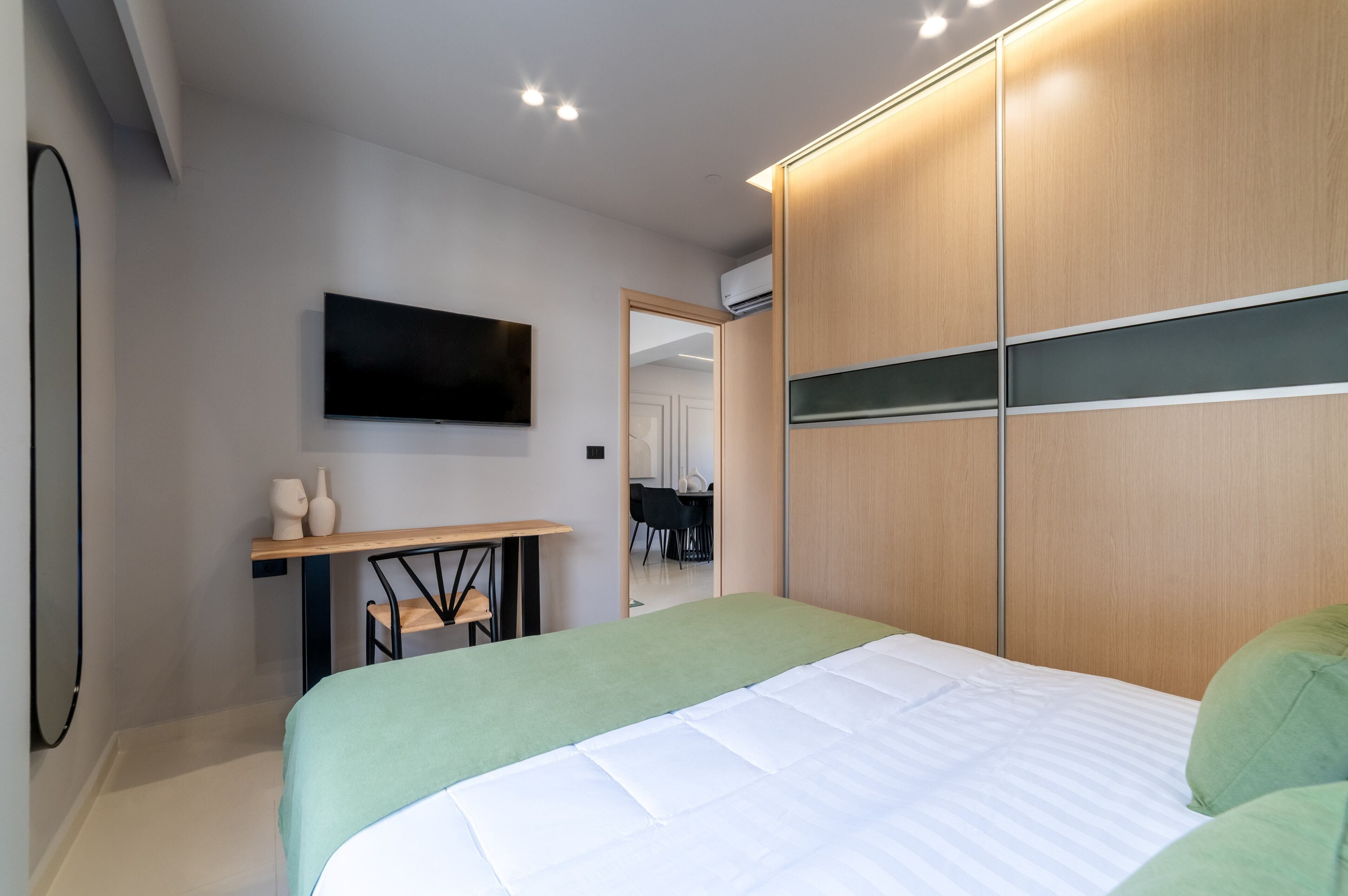 Camera da letto moderna con un letto, una TV, una scrivania e un armadio.