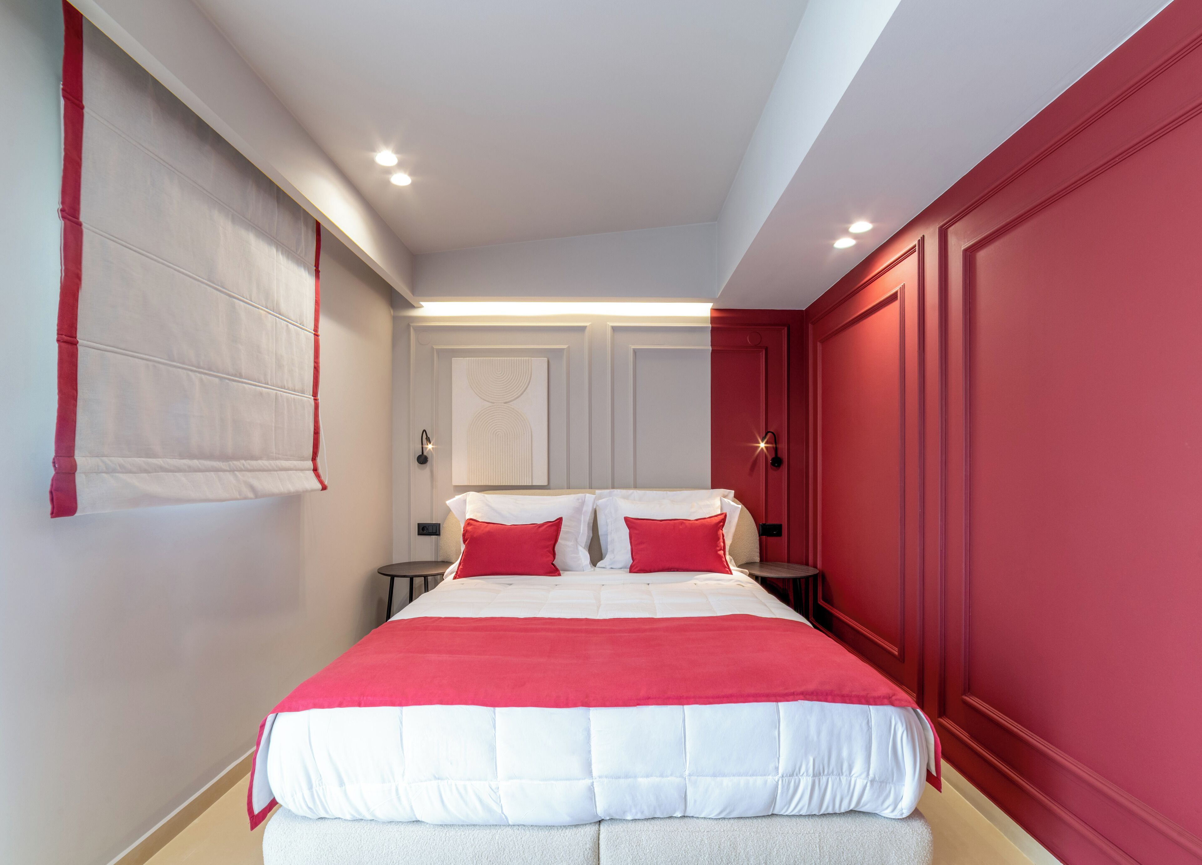 Ein Schlafzimmer mit einem Bett, Nachttischen und einer roten Wand.
