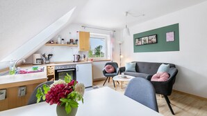 A modern kitchen with a dining area, a sofa, and a coffee table. - Apartment 'Dohle No 1' with Shared Terrace, Shared Garden and Wi-Fi (Vollerwiek)