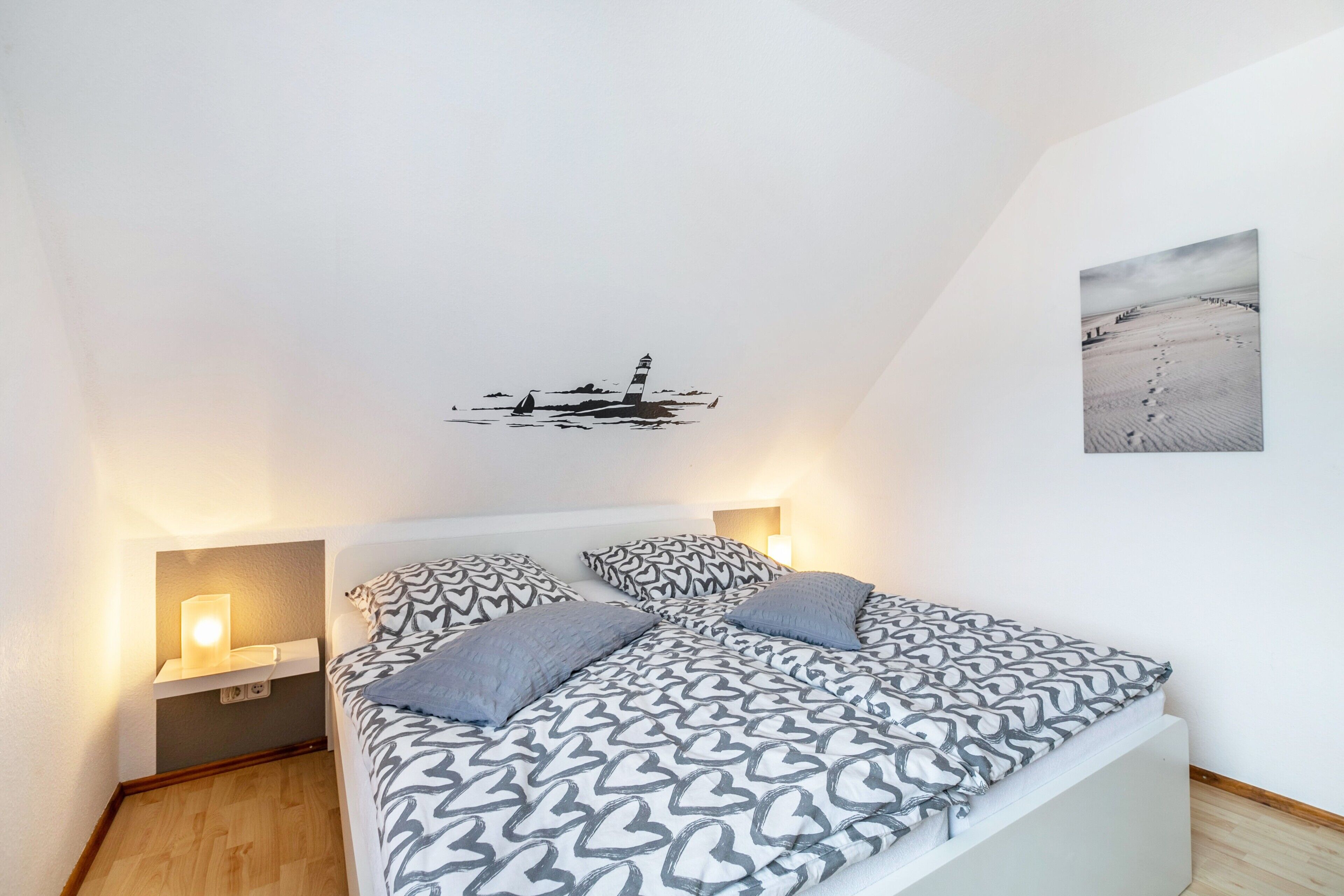 Une chambre à coucher avec un lit, une literie à motifs, un tableau accroché au mur et une table de chevet avec une lampe.