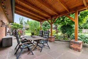 An outdoor patio with a wooden pergola, a table, and chairs. - Apartment 'Dohle No 1' with Shared Terrace, Shared Garden and Wi-Fi (Vollerwiek)