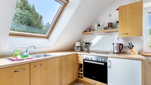 A kitchen with a skylight, wooden cabinets, a stove, and a coffee maker. - Apartment 'Dohle No 1' with Shared Terrace, Shared Garden and Wi-Fi (Vollerwiek)