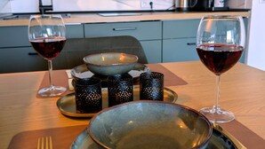 Una mesa de comedor con un bol, dos copas de vino tinto, un tenedor y un cuchillo.