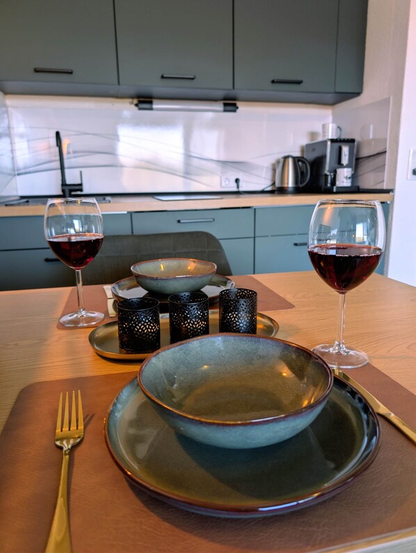 A dining table with a bowl, two glasses of red wine, a fork, and a knife. - cozy MeLou Fewo Harzruhe Wellness (Bad Lauterberg)