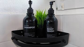 Twee zwarte flessen shampoo en douchegel op een zwarte dienblad, met een plantje.