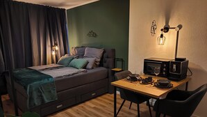 Un dormitorio compacto con cama, mesita de noche y un pequeño comedor con mesa y sillas.