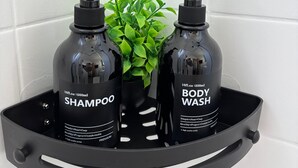 A black bathroom shelf with two bottles of shampoo and body wash, and a small potted plant. - MeLou Fewo NaturQuartier Wellness (Bad Lauterberg)