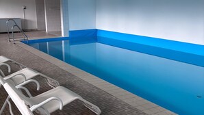 A swimming pool with a blue interior, surrounded by white lounge chairs.