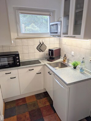 A kitchen with white cabinets, a microwave, a toaster, and a sink. - MeLou Fewo NaturQuartier Wellness (Bad Lauterberg)
