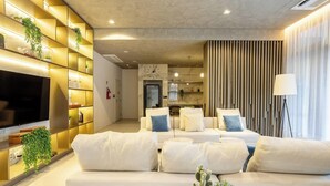 A modern living room with a sofa set, a flat-screen TV, and a wall-mounted shelf with plants. - Your Perfect and Exclusive Stay in the Heart of Itaim Bibi - DSG (São Paulo)