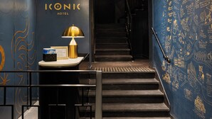 Eine Hotelhalle mit einer Treppe, einem Empfangstresen und einer Wand mit dekorativer Schrift.