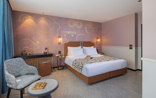 Una habitación de hotel con una cama, un escritorio, una silla y una pequeña mesa.