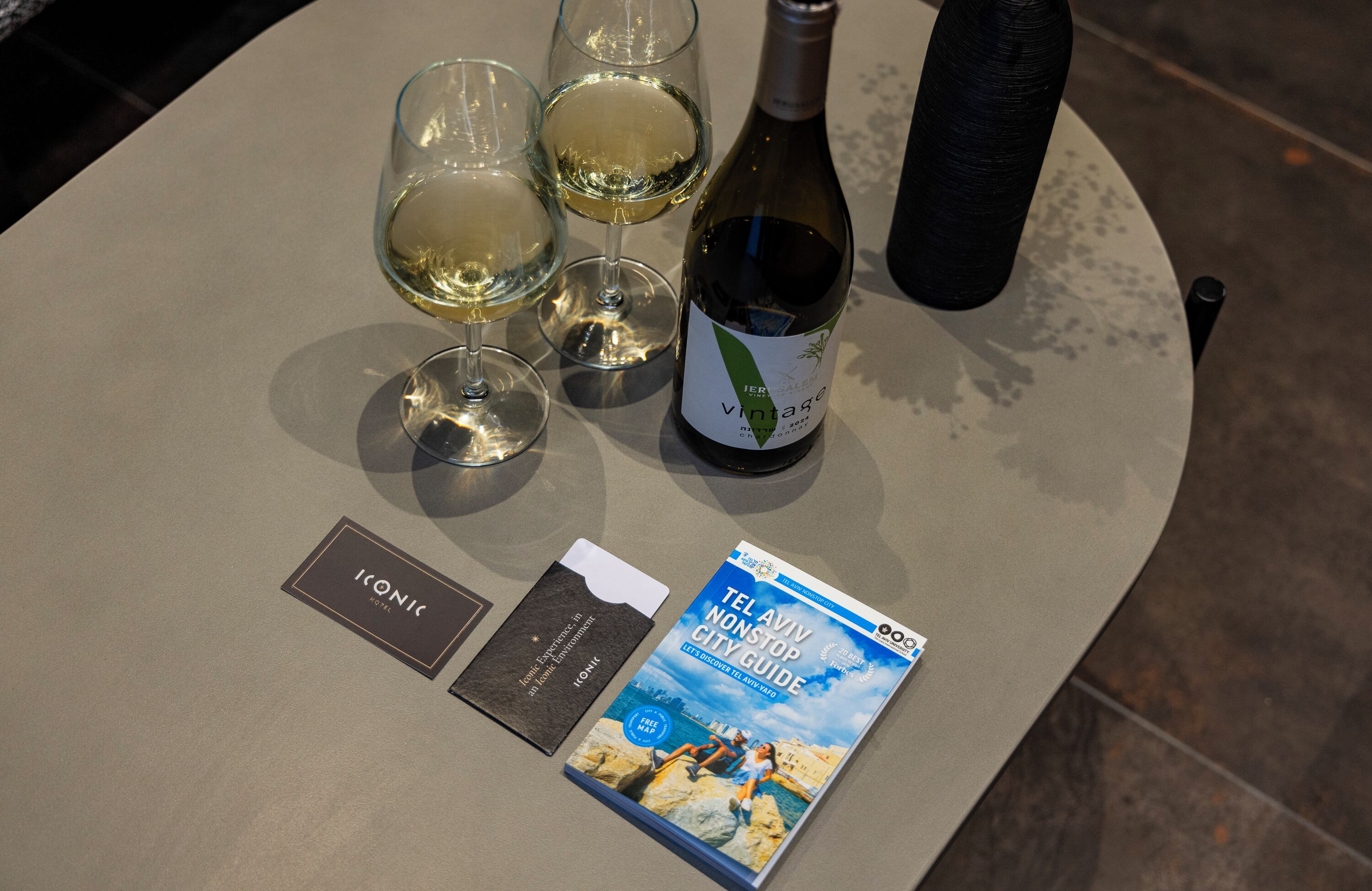Een tafel met een fles wijn, drie wijnkannen, een boekje en een kaartje.