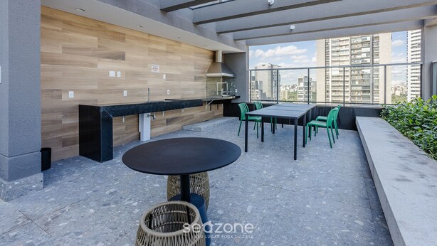 A modern outdoor patio with a dining area, a built-in kitchen, and a view of the cityscape. - Modern and Fully Equipped Apartments, With Leisure Facilities and in the Best Location in Pinheiros - SP - EGP (São Paulo)