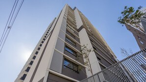 A tall, modern building with a prominent vertical design, featuring multiple windows and a metal fence in the foreground. - Modern and Fully Equipped Apartments, With Leisure Facilities and in the Best Location in Pinheiros - SP - EGP (São Paulo)