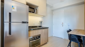 A modern kitchen with a built-in refrigerator, oven, and microwave. There is a dining area with a table and chairs. - Modern and Fully Equipped Apartments, With Leisure Facilities and in the Best Location in Pinheiros - SP - EGP (São Paulo)