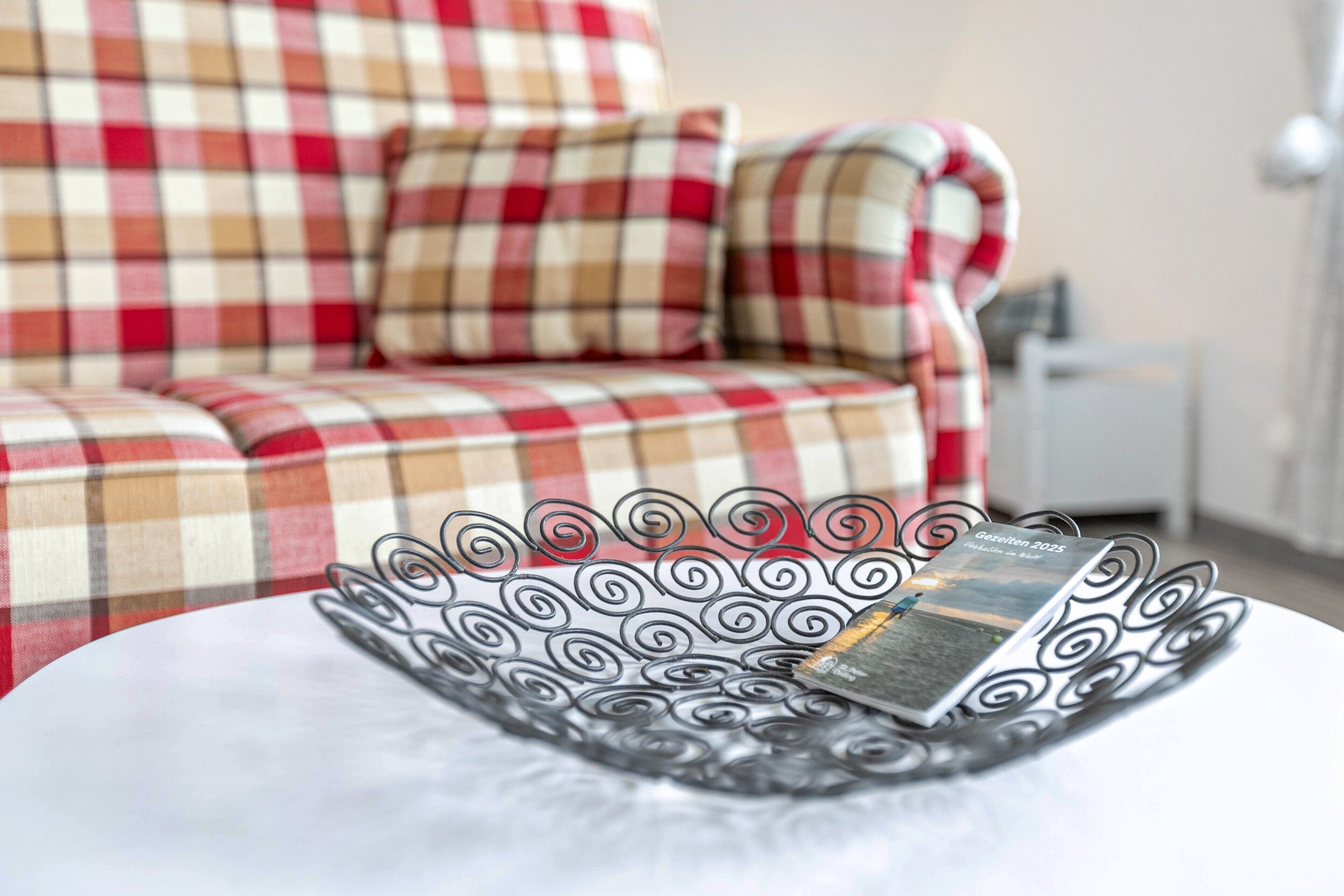 A checkered sofa with a magazine on a tray.
