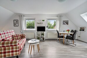 A living room with a sofa, a table, a TV, and a dining area with chairs. - Apartment 'Dohle No 2' with Shared Terrace, Shared Garden and Wi-Fi (Vollerwiek)