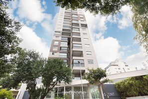 A modern high-rise building with multiple balconies and large windows, surrounded by trees. - Beautiful Studio 400m From the Metro Eatnr0205 (São Paulo)
