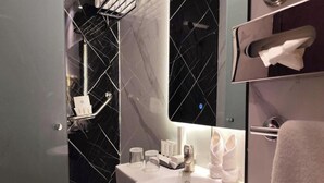 Ein modernes Badezimmer mit Marmorverkleidung, einem weißen Waschbecken und einem Handtuchhalter.