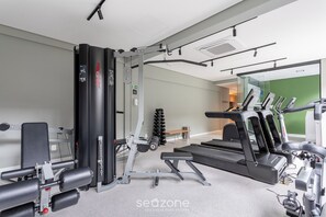 A gym with exercise equipment, a treadmill, and a bench. - Modern in Ecos Vila Madalena Cond. Evm1012 (São Paulo)
